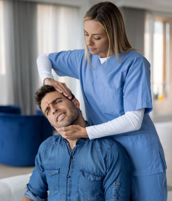 Physical therapist adjusting the neck of a patient at home during a house call â healthcare and medicine concepts
